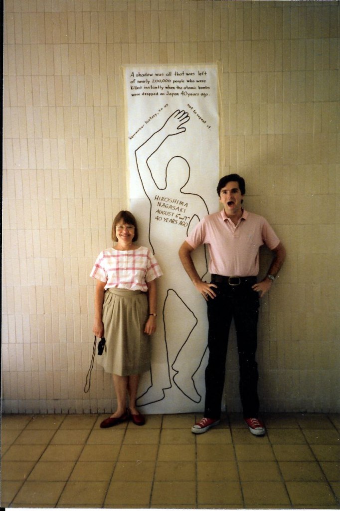 Image:

The two of us posing with life-size poster of a human form traced on paper with the words:

A shadow was all that was left of nearly 200,000 people who were killed instantly when the atomic bombs were dropped on Japan 40 years ago.

Remember history so as not to repeat it.

Hiroshima Nagasaki August 6th and 9th 40 years ago.